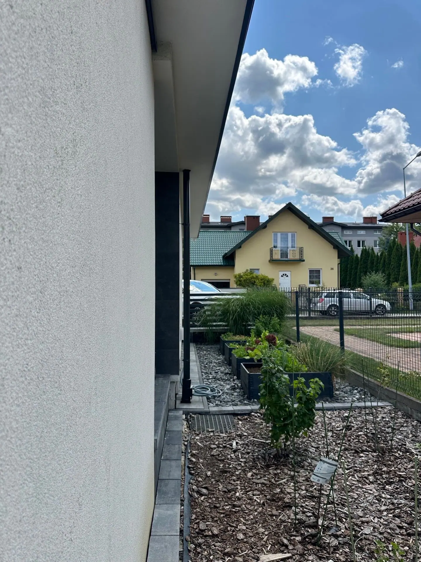 Rabata ściółkowana korą z młodymi nasadzeniami wzdłuż elewacji domu