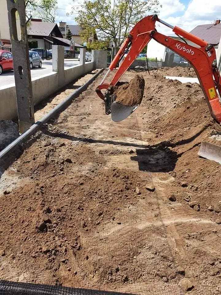 Minikoparka wykonująca wykop pod instalację przy krawężniku
